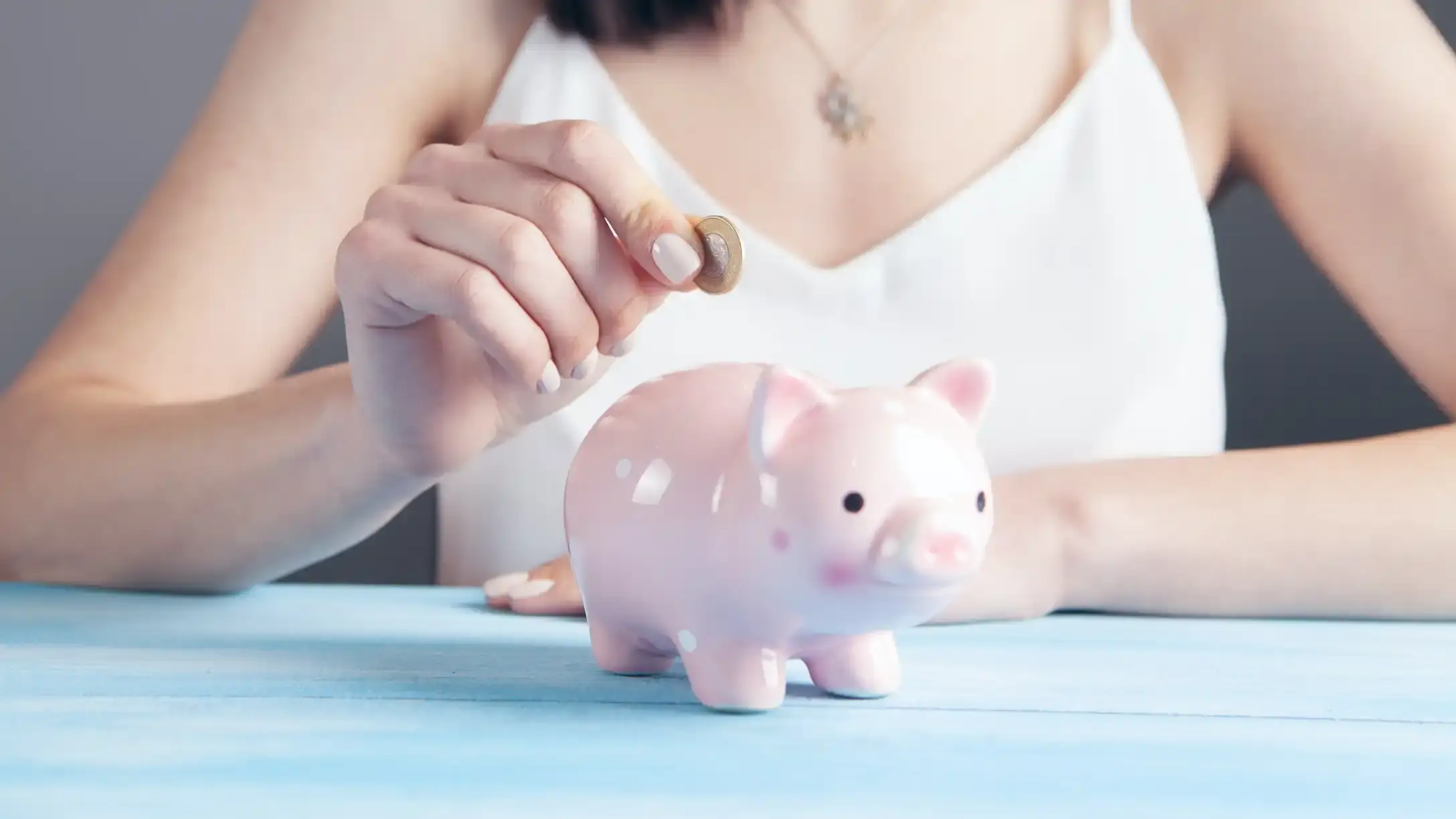 A person putting a coin in a piggy bank