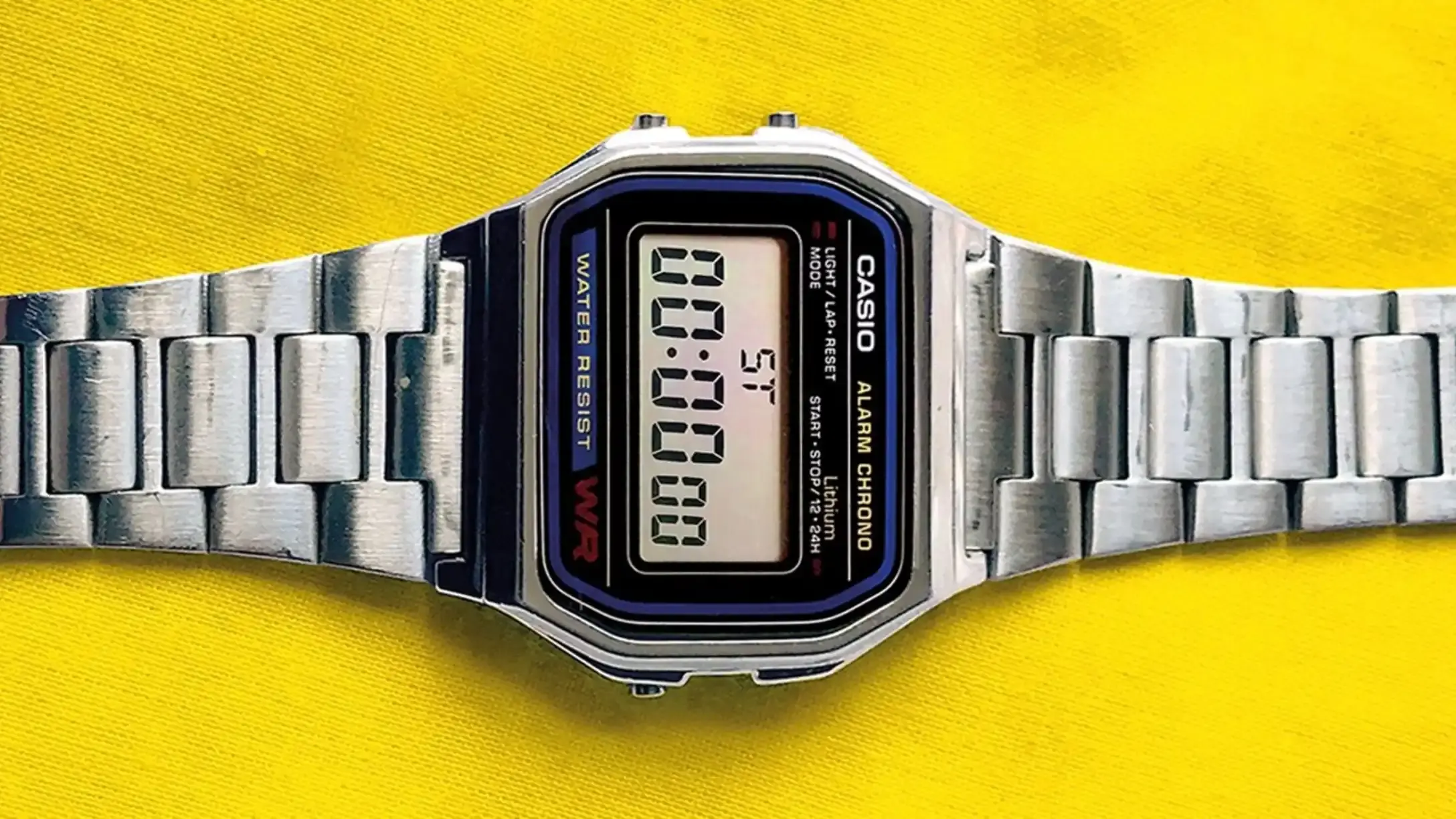 A digital watch laying flat on a yellow surface