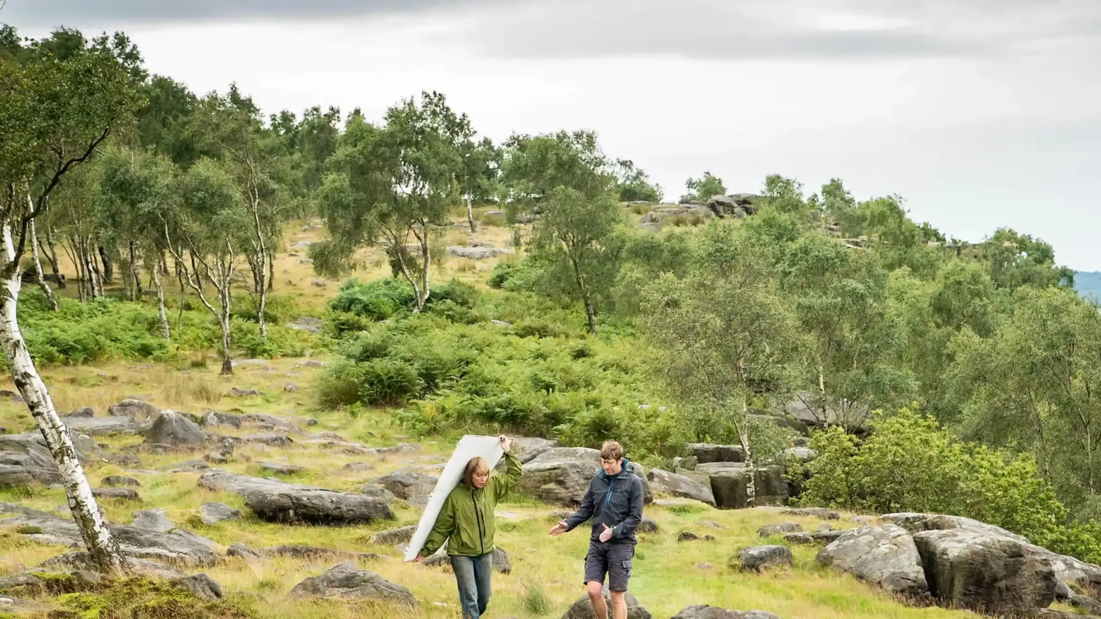 Two people standing on a tree-covered hill top