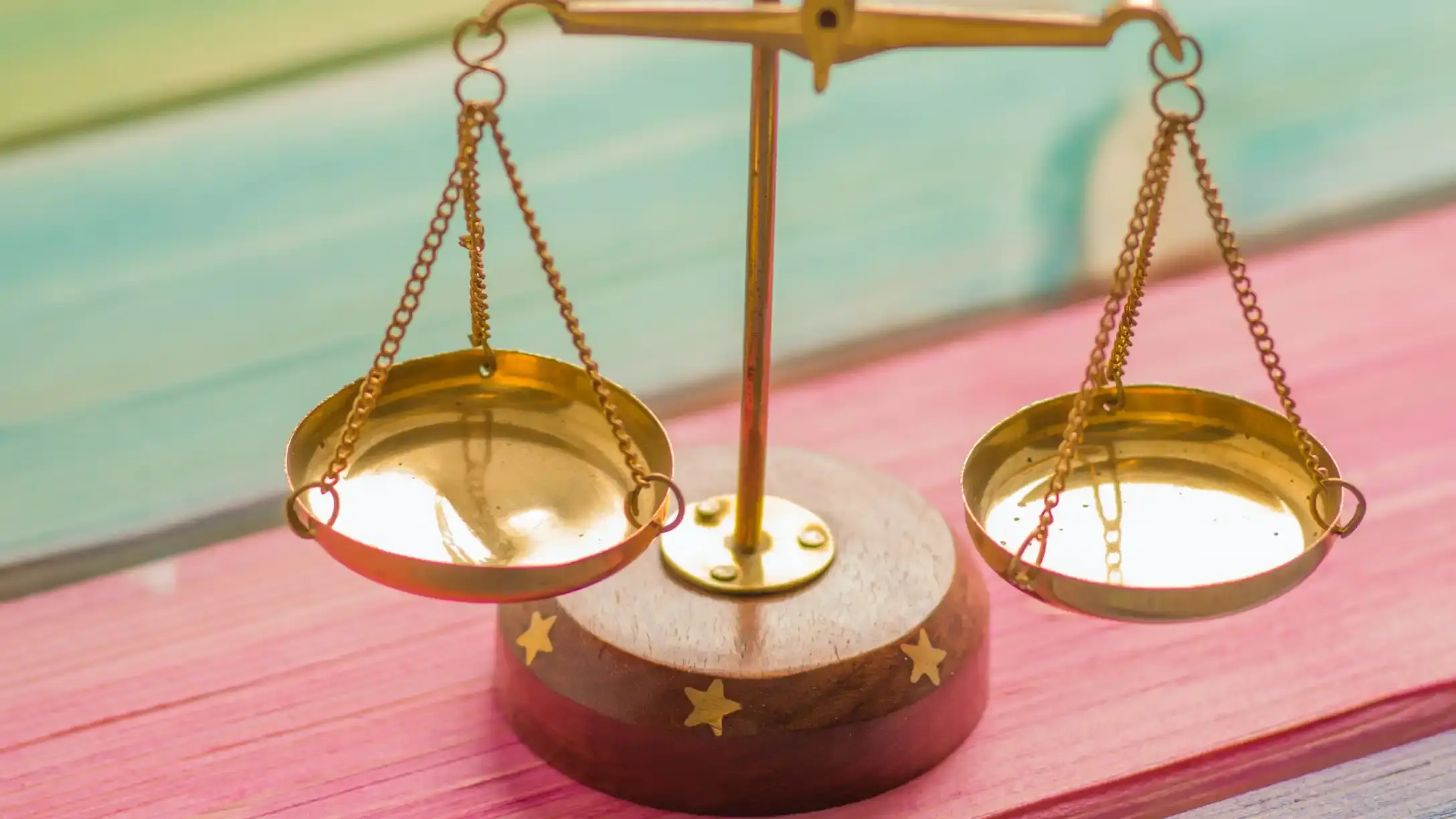 A set of brass scales sitting on a rainbow painted table