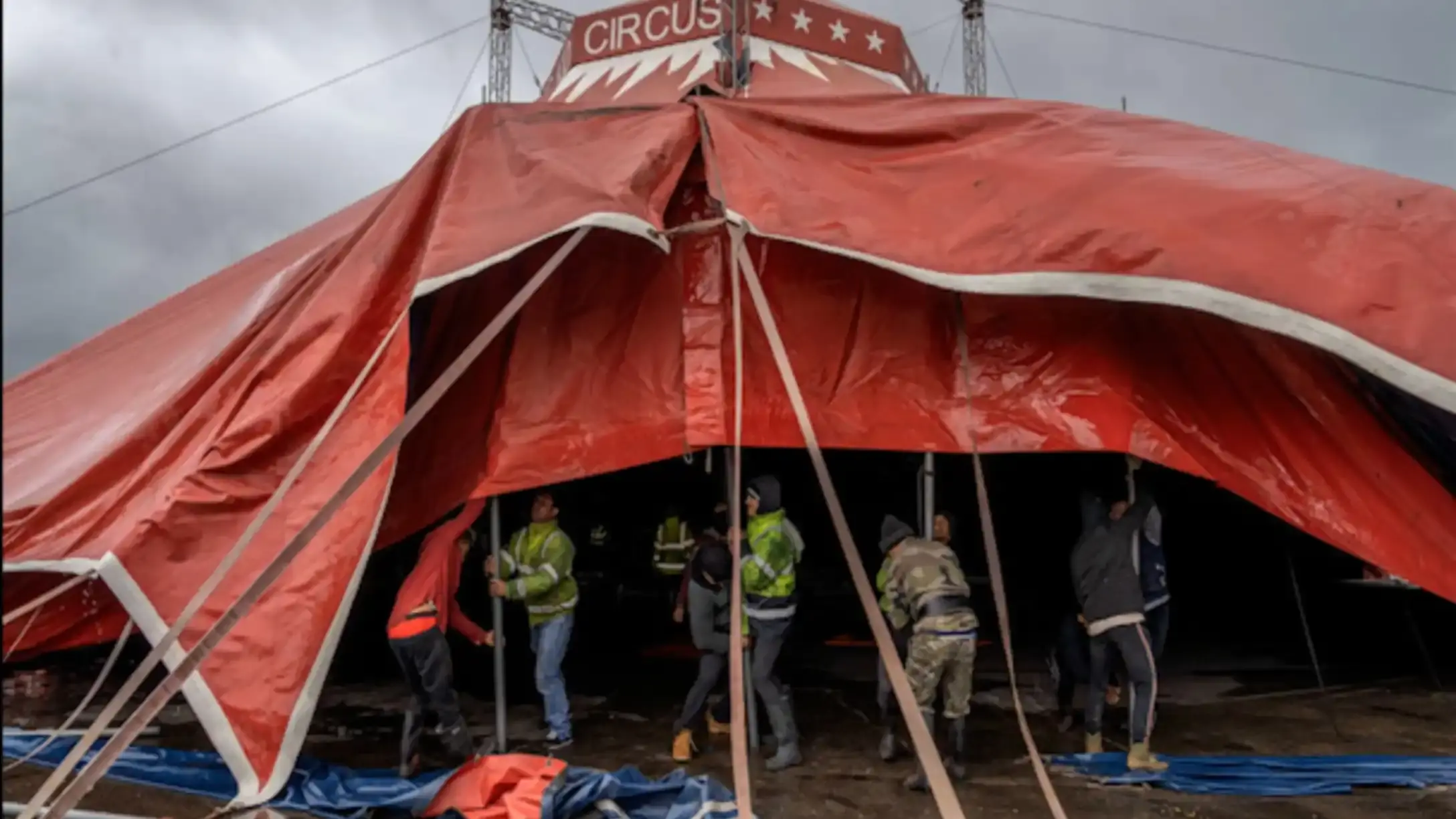 Circus tent being erected with workers underneath