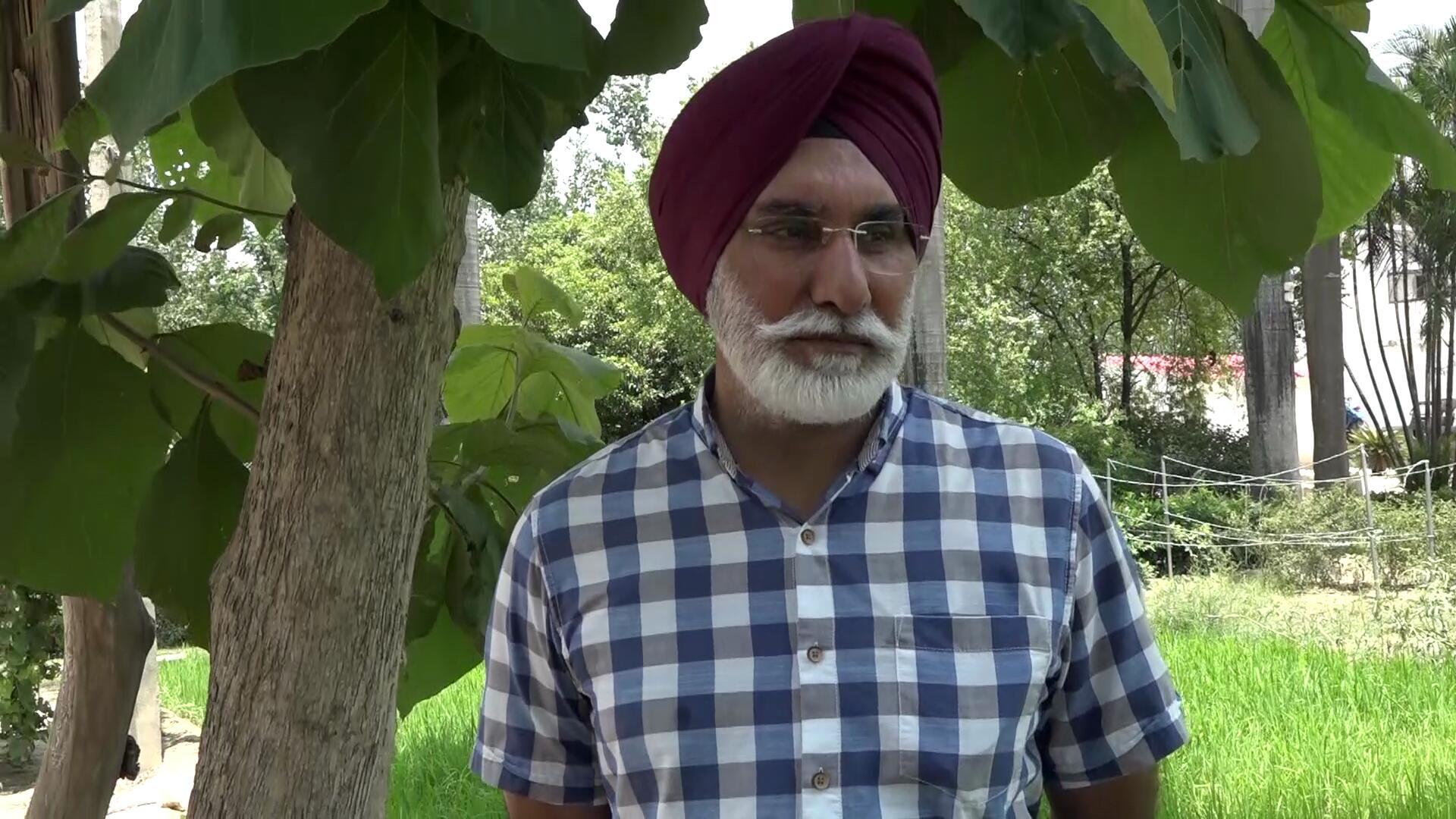 a picture of an indian man wearing a blue check shirt and a red turban
