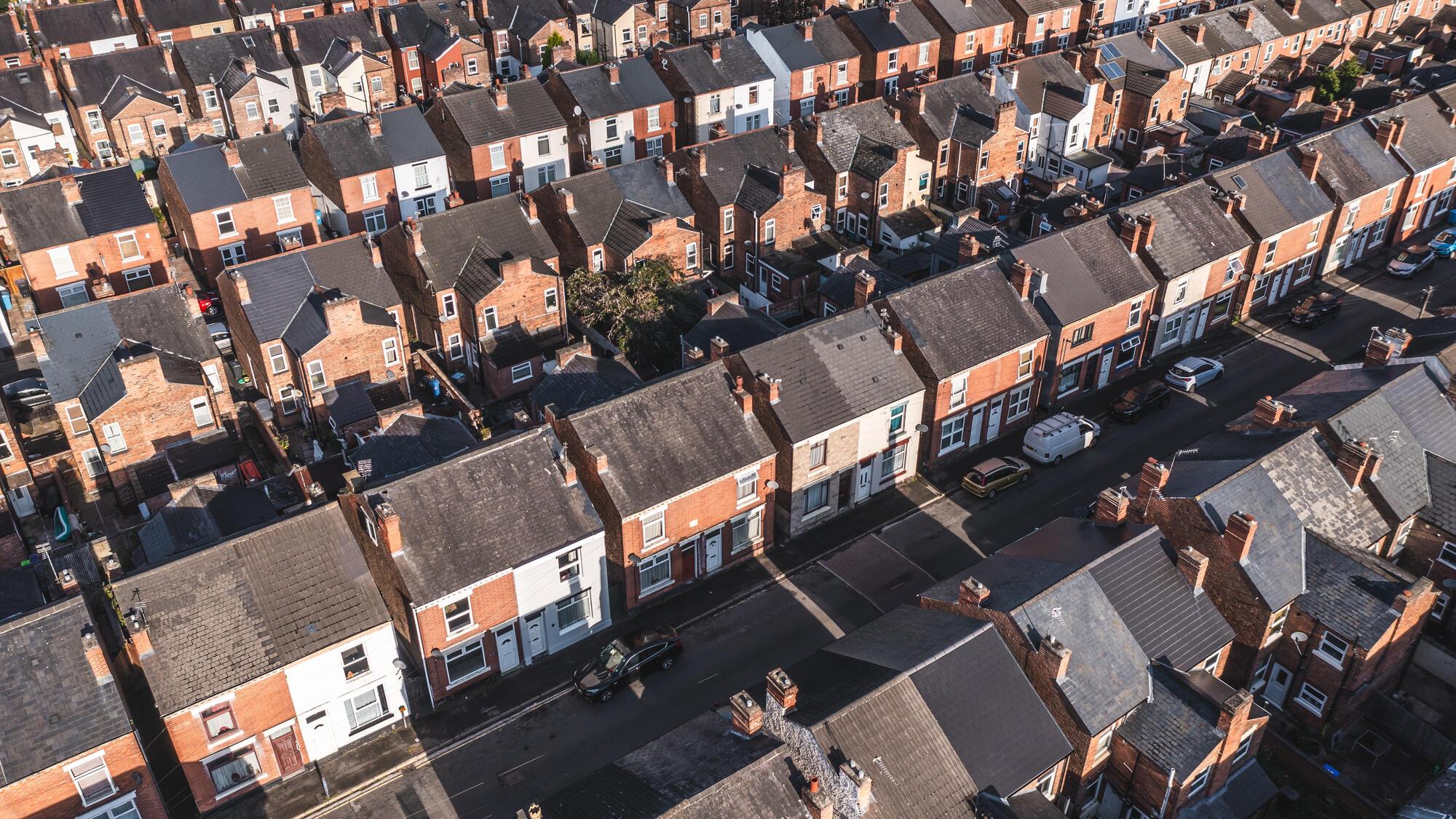 Aerial view above rows of back to back terraced houses on a large council estate