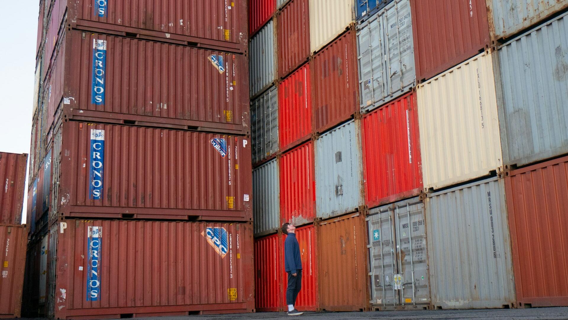 Man looking up at many shipping containers