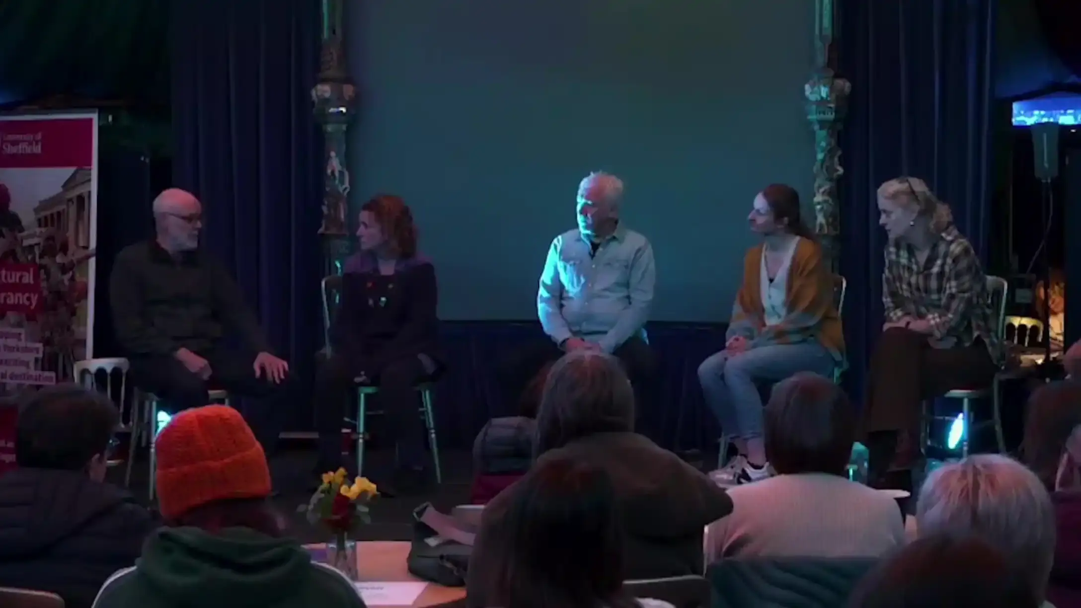 Photo of five people on stage with the audience in the foreground