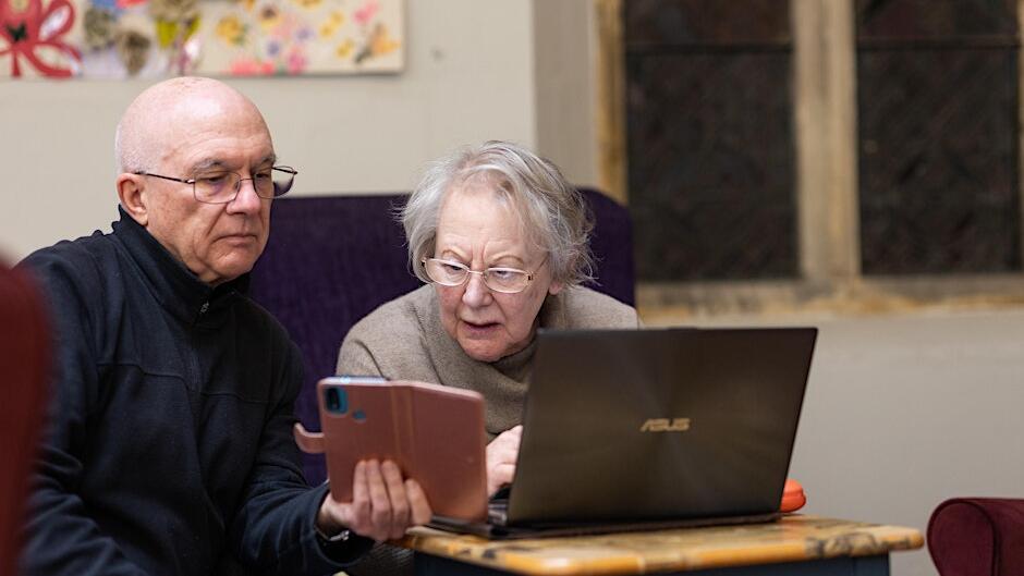 An older man and women sit in front of a laptop