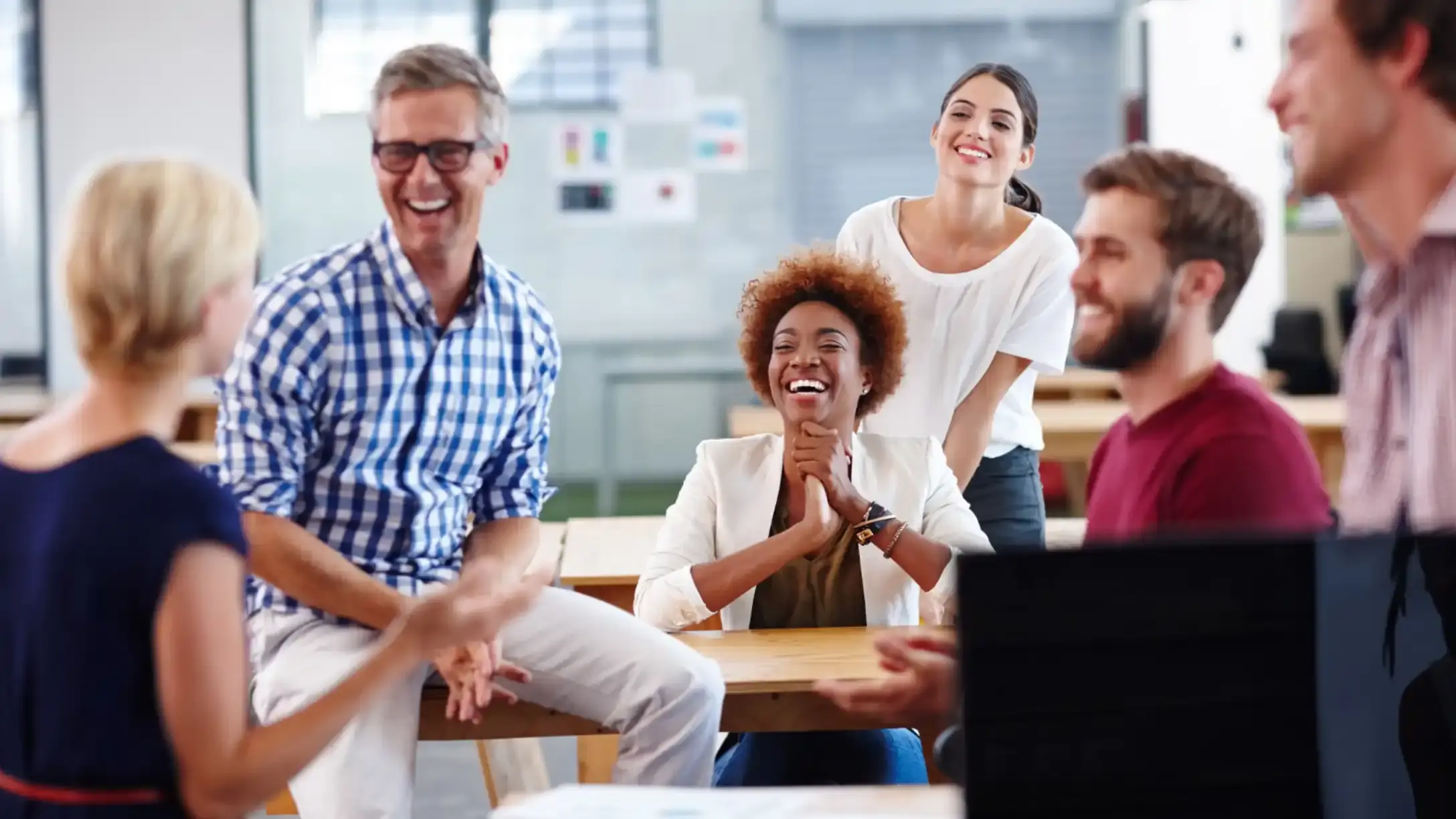 Six people sitting in a meeting room, talking and smiling at one another