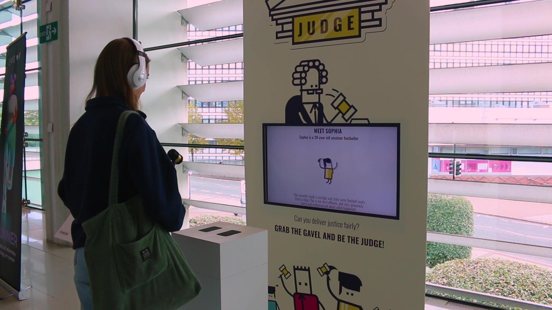 A female holding a gavel in front of an interactive exhibit