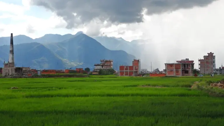 landscape of damaged buildings in a field with mountains in the distance