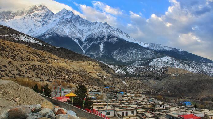 A settlement in Nepal beneath a snow-topped mountain range