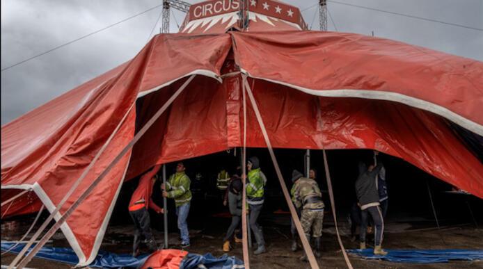 Circus tent being erected with workers underneath