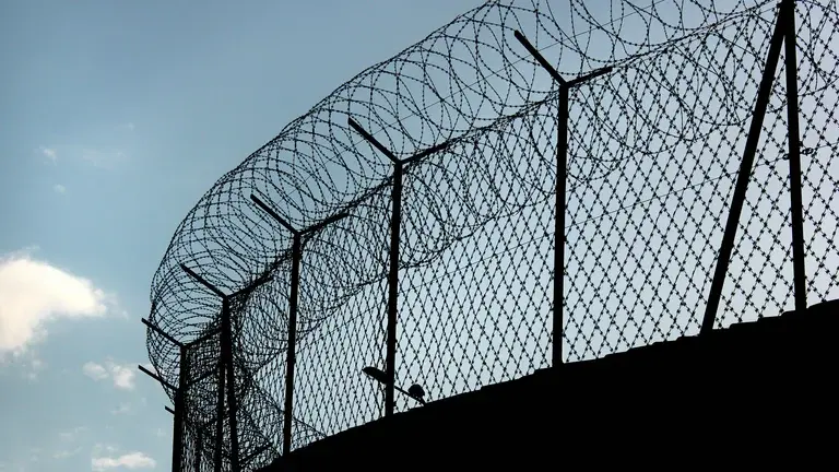 Tall fence with barbed wire