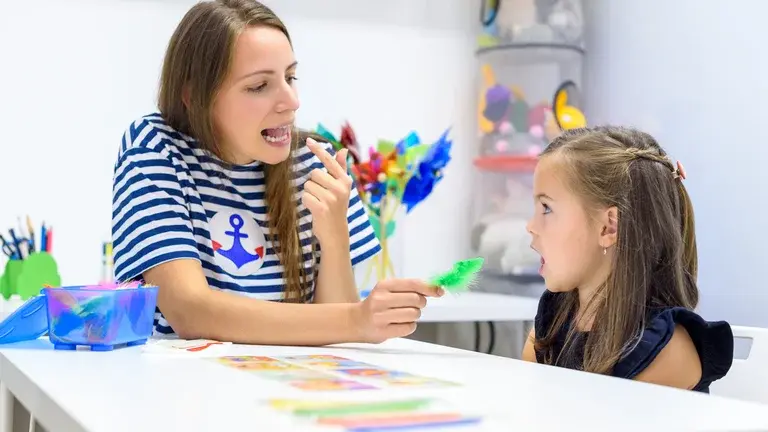 Adult working with child and pointing to her mouth