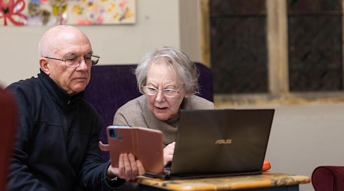 An older man and women sit in front of a laptop