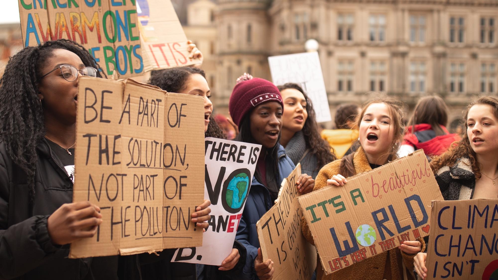 A group of young people at a protest holding placards about climate change