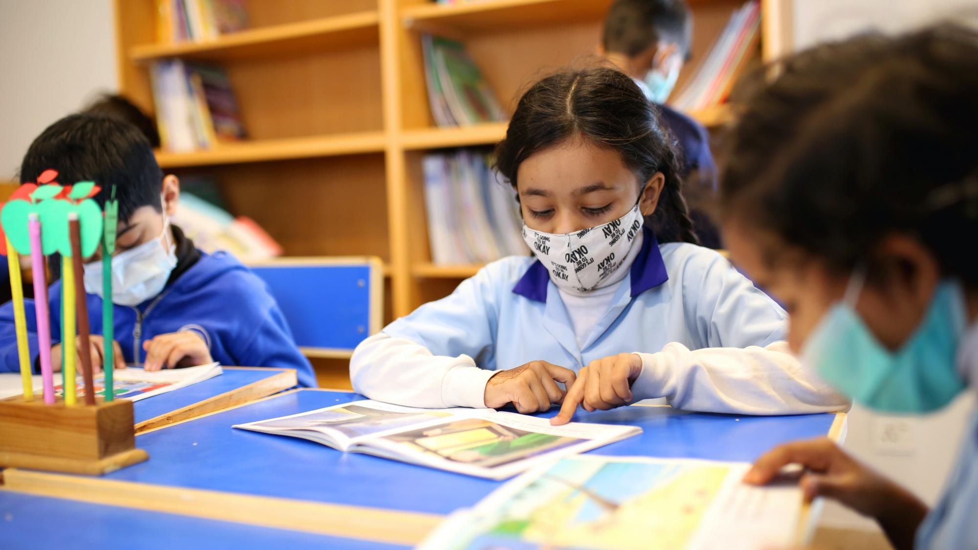 Children wearing face masks and reading books in school
