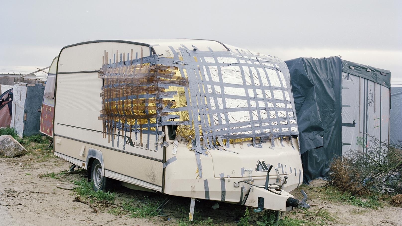 A caravan with taped-up windows in a refugee camp