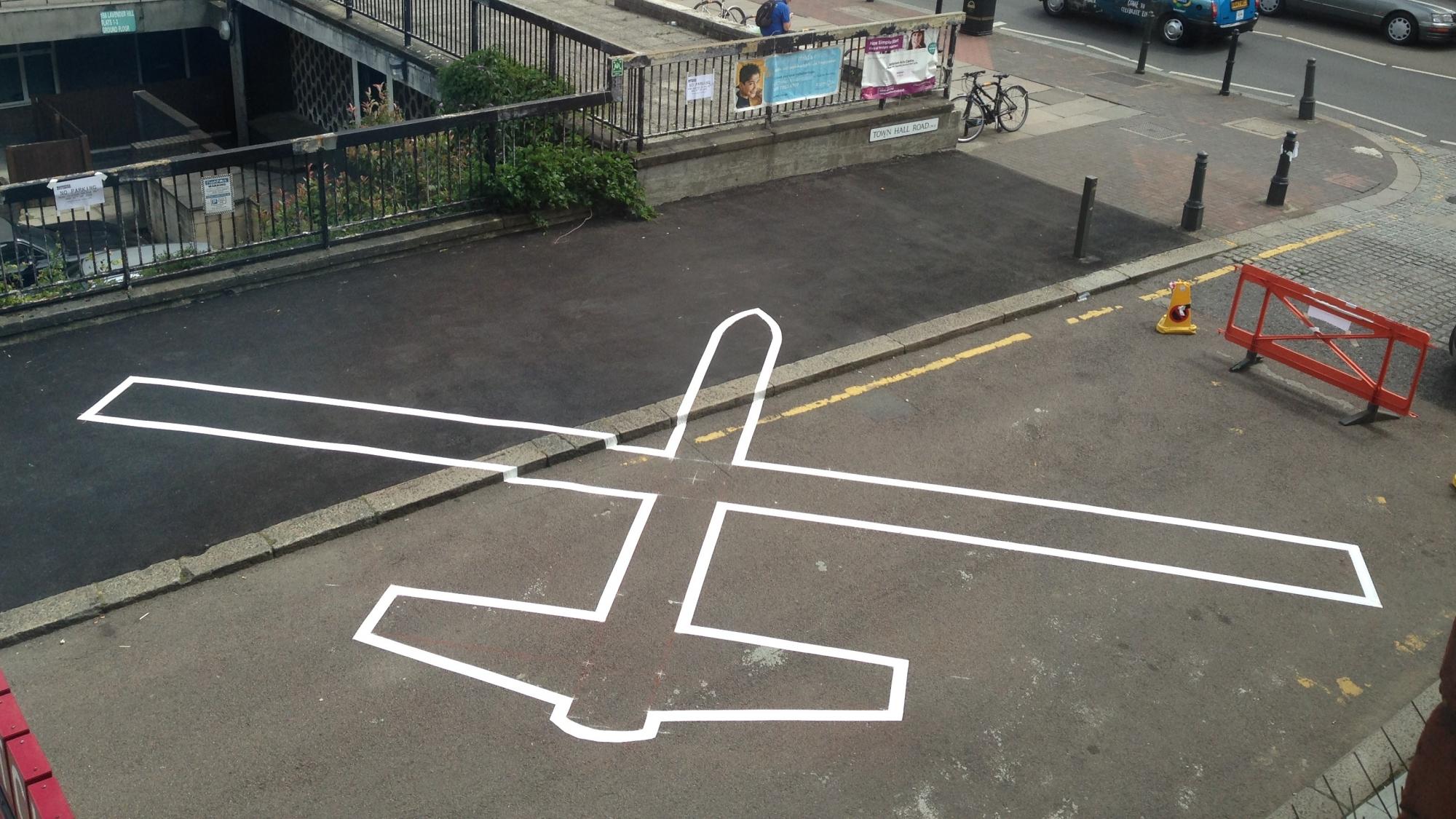 The outline of a drone painted onto a road 