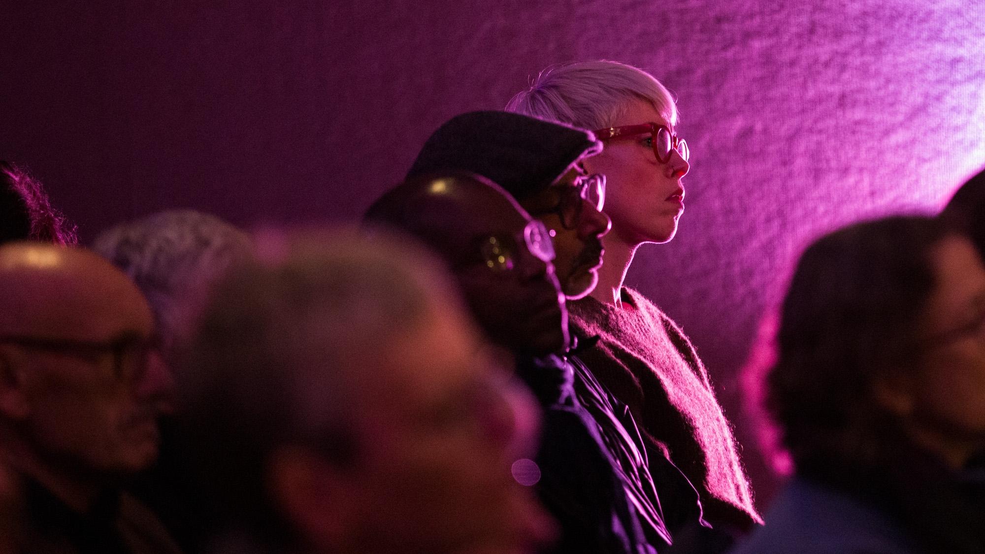 An audience bathed in purple light