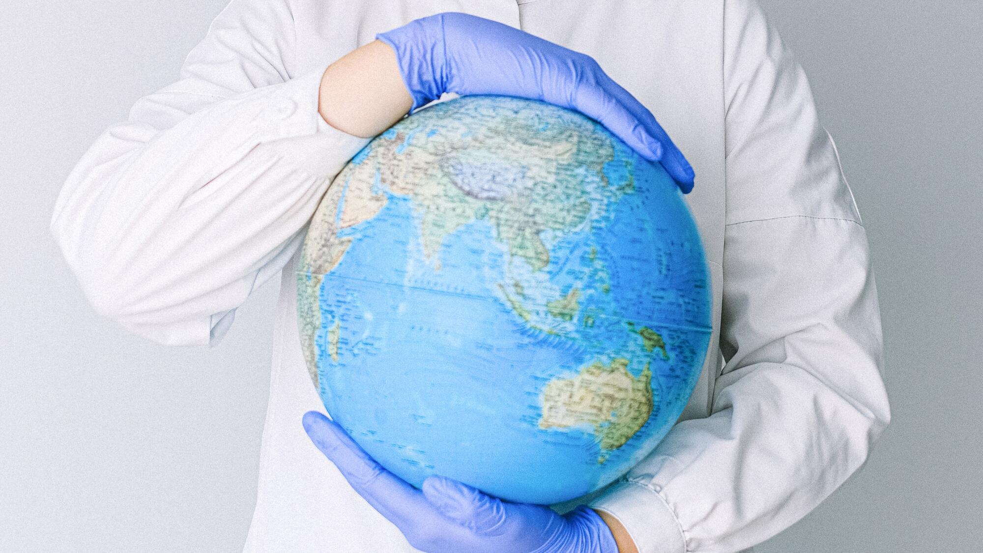 A person wearing blue medical gloves holding a globe