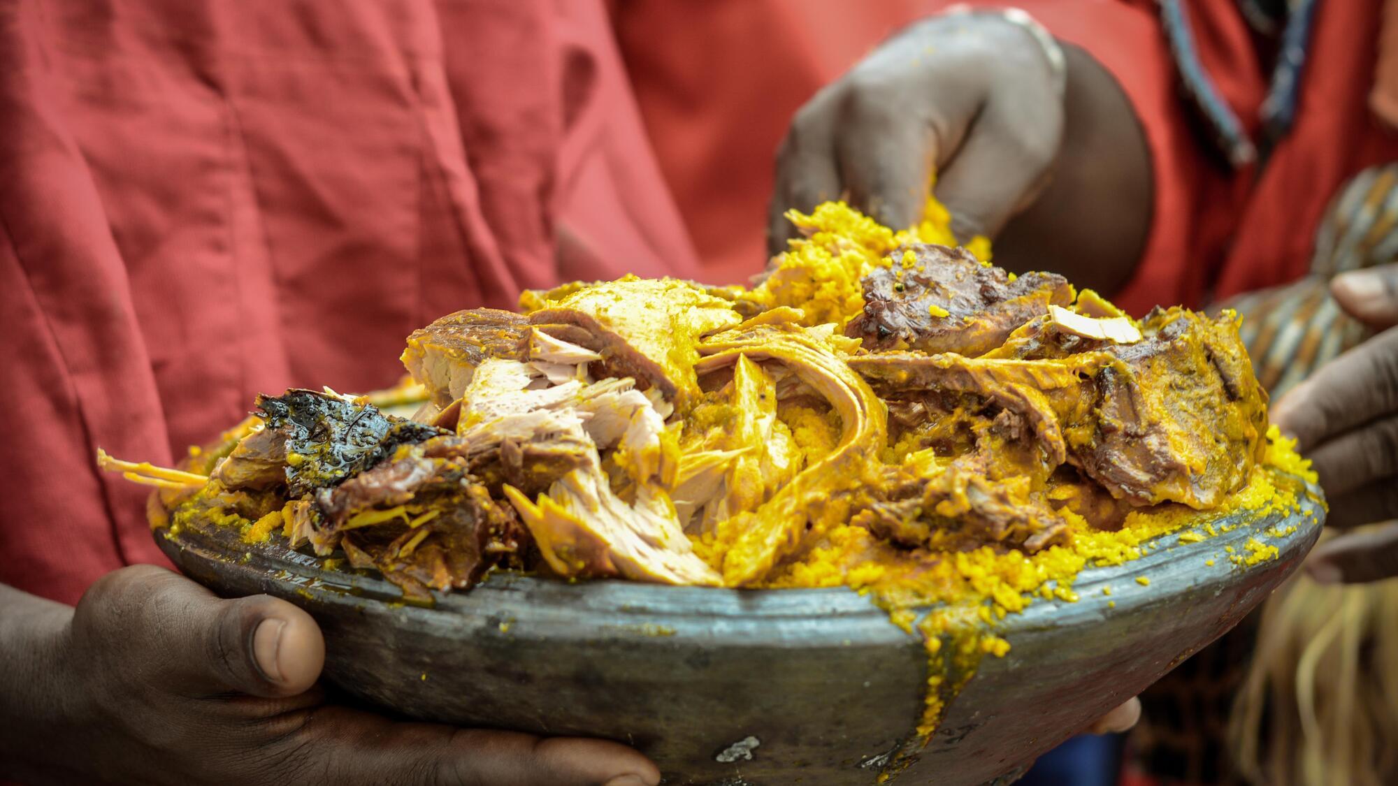 A person holding a large bowl of a rice and meat dish