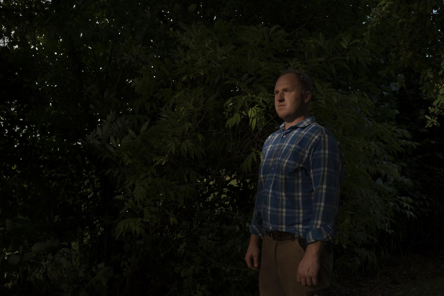 A man standing next to a hedge