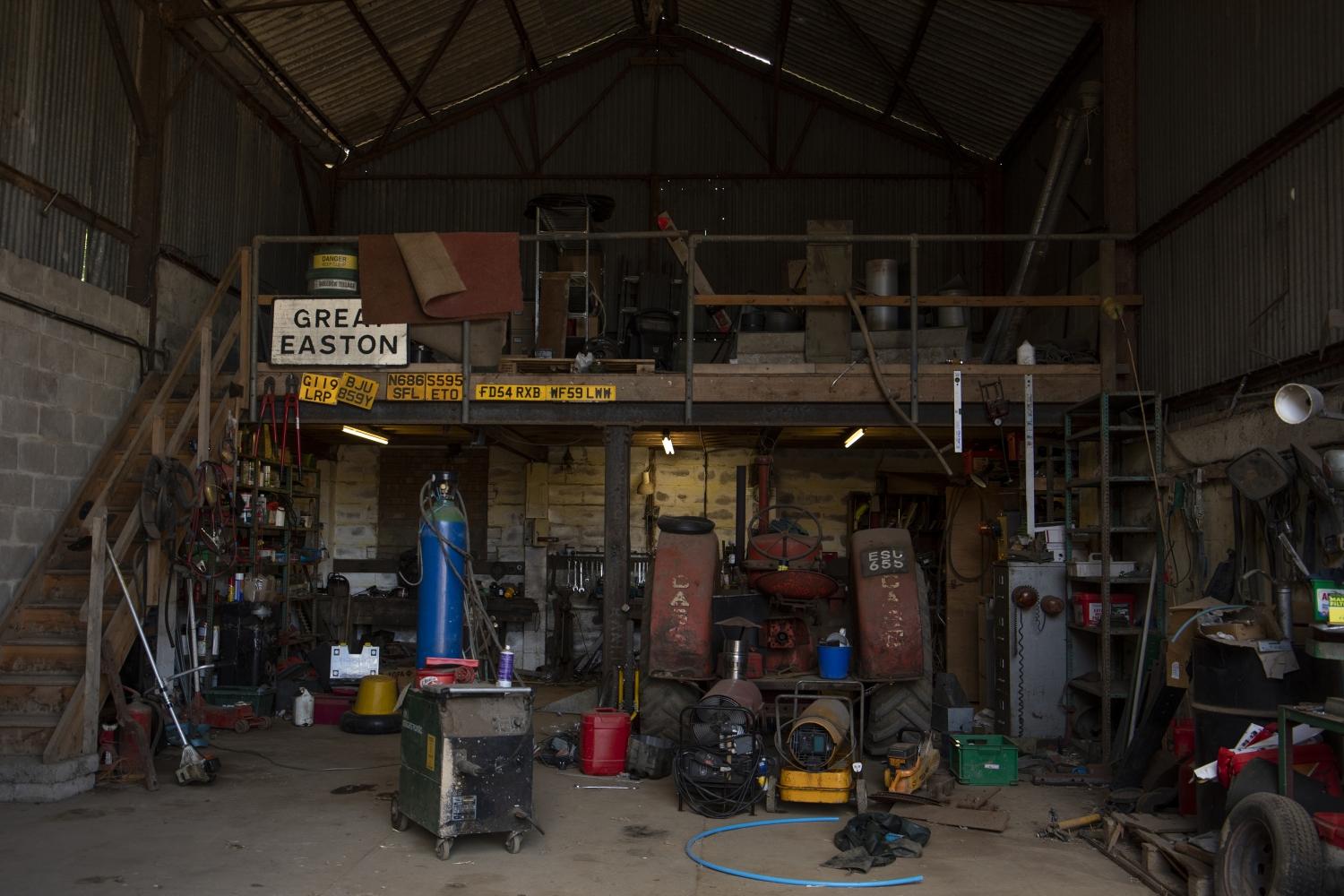 A barn full of tools, machinery and a tractor