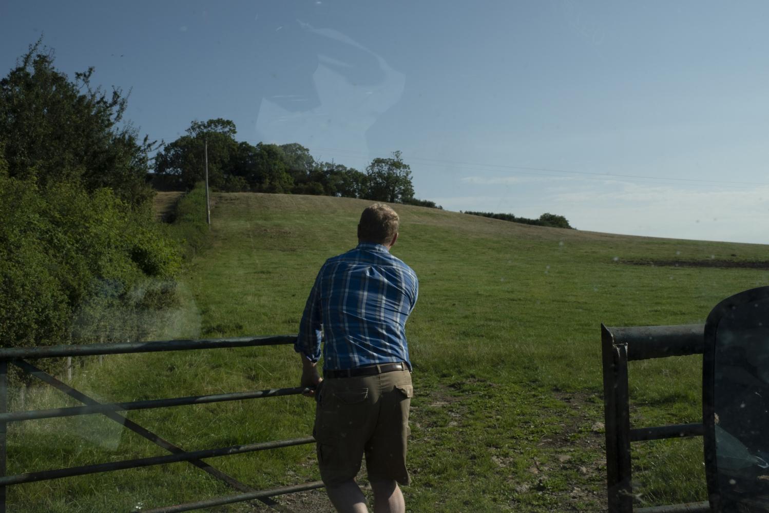 A man opening a gate into a field