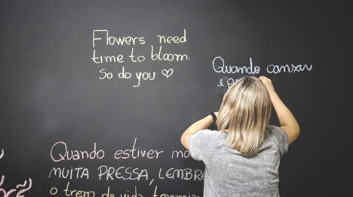 A teacher writing phrases in difference languages on a blackboard