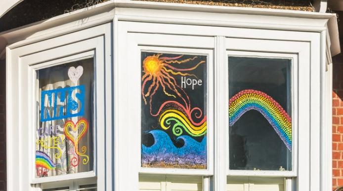 A window with 'NHS' and rainbows painted on it