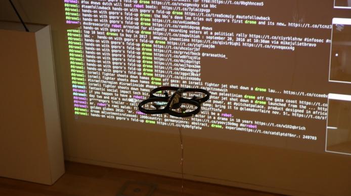 A drone hovering in front of a projection displaying web data