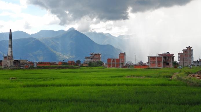 landscape of damaged buildings in a field with mountains in the distance