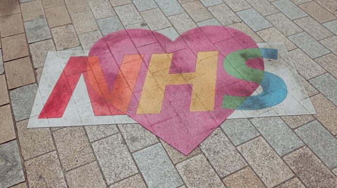 An NHS logo with love heart design on the pavement