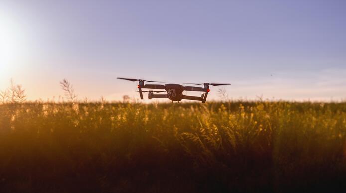 A drone hovering low over a field on a clear day