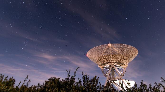 A large radio telescope facing up into the night sky