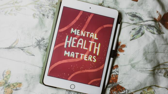 An iPad with the words 'mental health matters' on the screen laying on a blanket