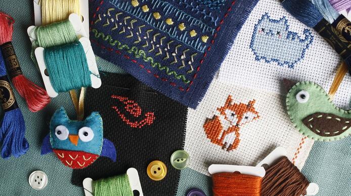 A collection of embroidered animals and embroidery needles an thread