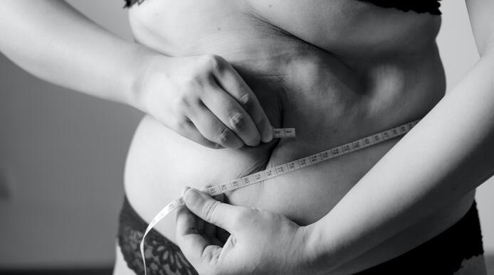 A woman holding a measuring tape around her stomach