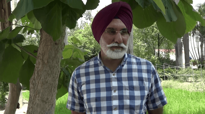 a picture of an indian man wearing a blue check shirt and a red turban